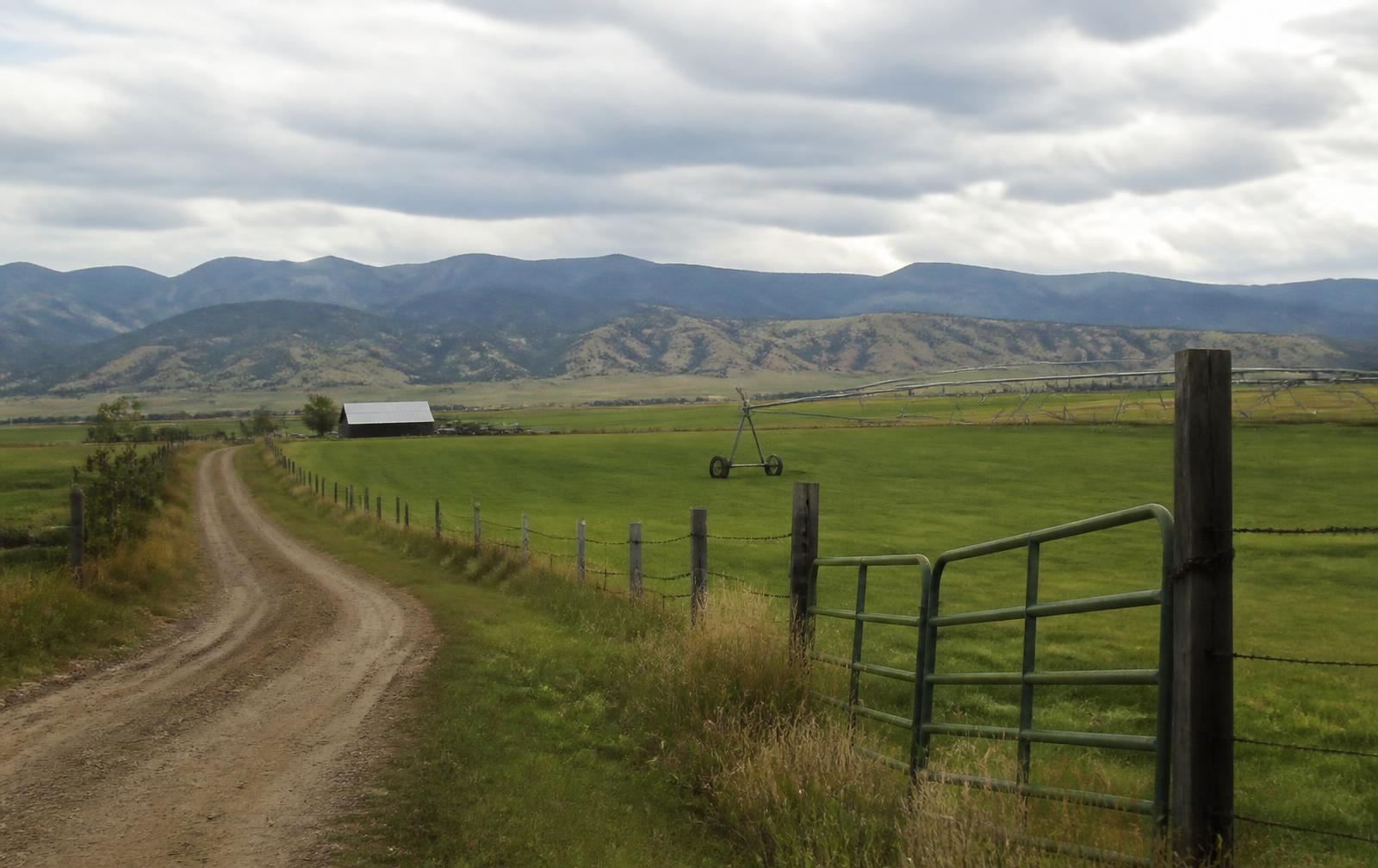 Dirt ranch road and fenced hay pasture on a working rural property in Southwest Colorado